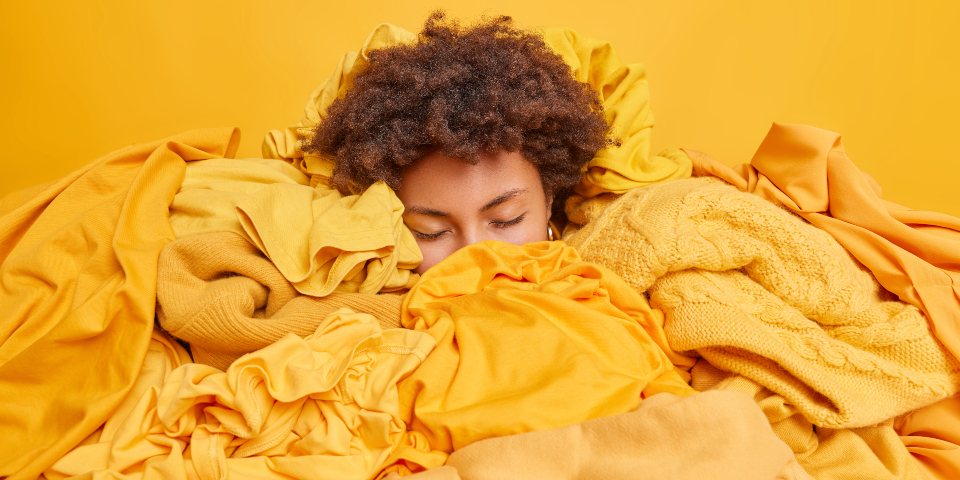 Woman with afro hair on top of yellow garments with a yellow wall behind
