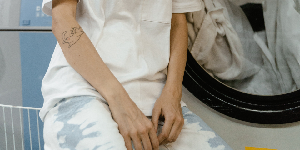 Young woman sitting next to self-service washing machine