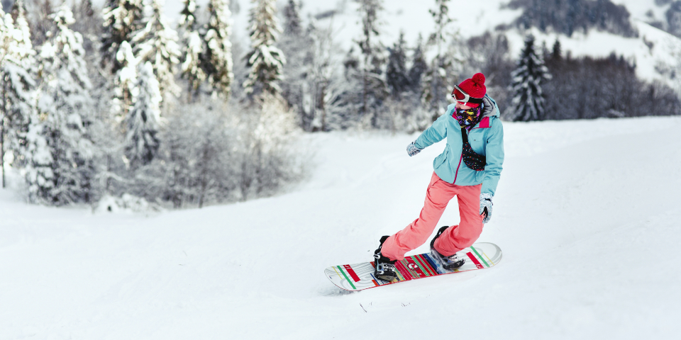 Woman in ski suit going down the hill on her snowboard